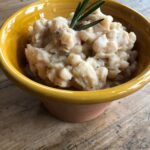 Cannellini bean dip topped with olive oil and a sprig of fresh rosemary.