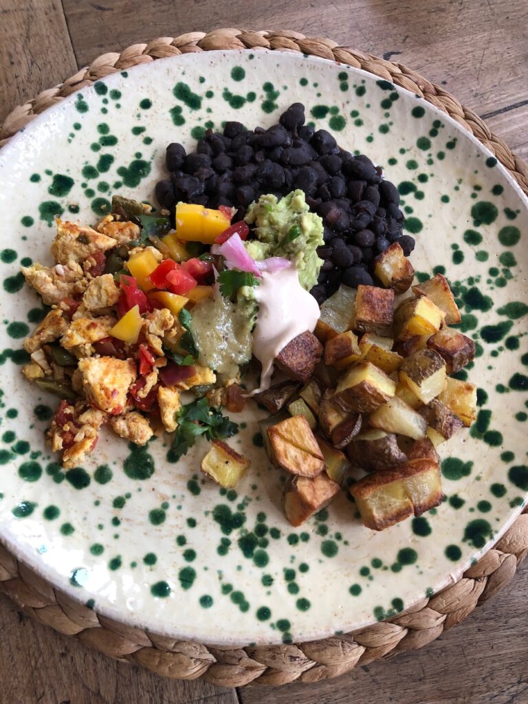 Nopale tofu scramble with black beans, roasted potatoes, green salsa, mango pico, guacamole and chipotle crema.