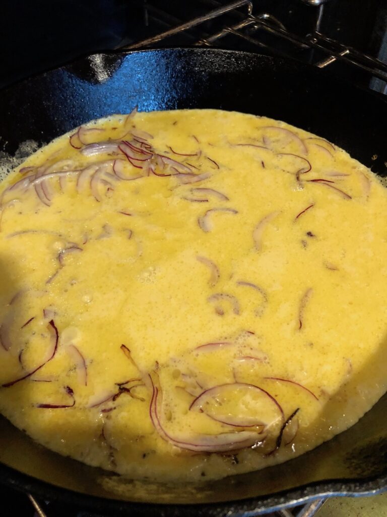 Farinata batter with thinly slice red onion