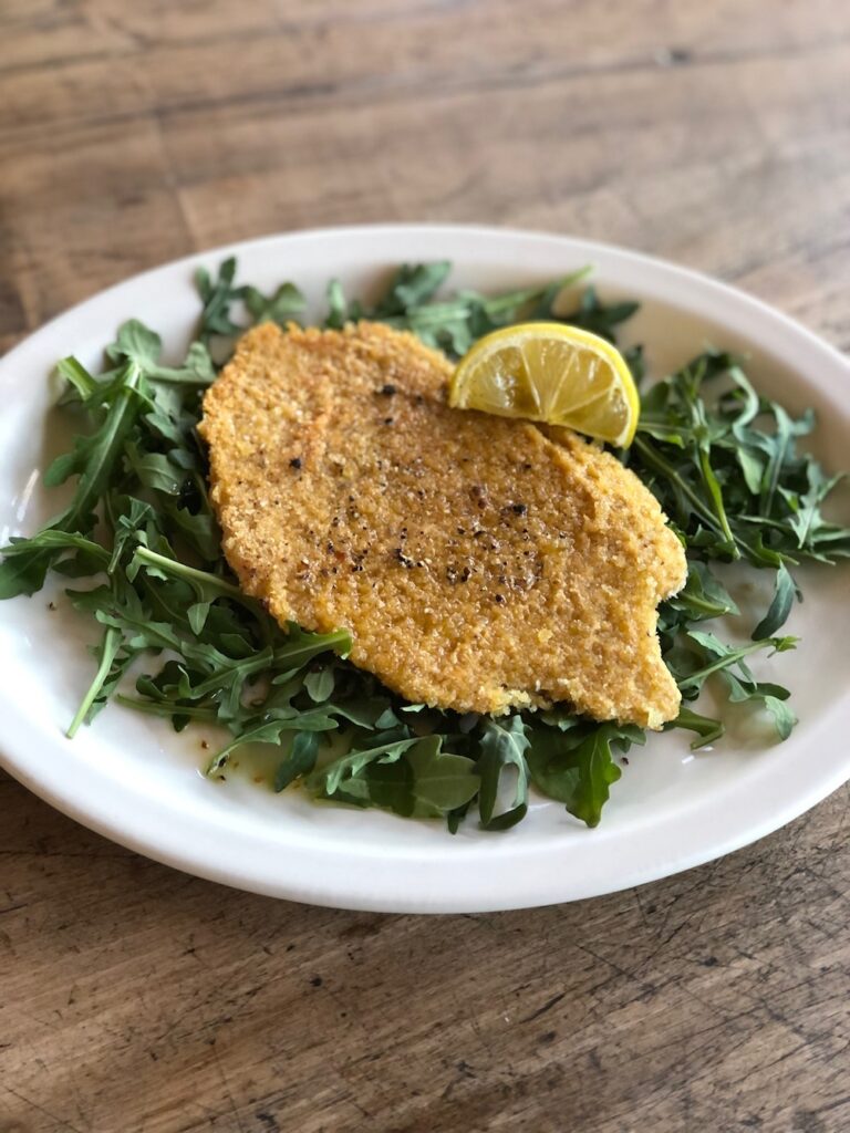 chickpea cutlet served on a bed of arugula.