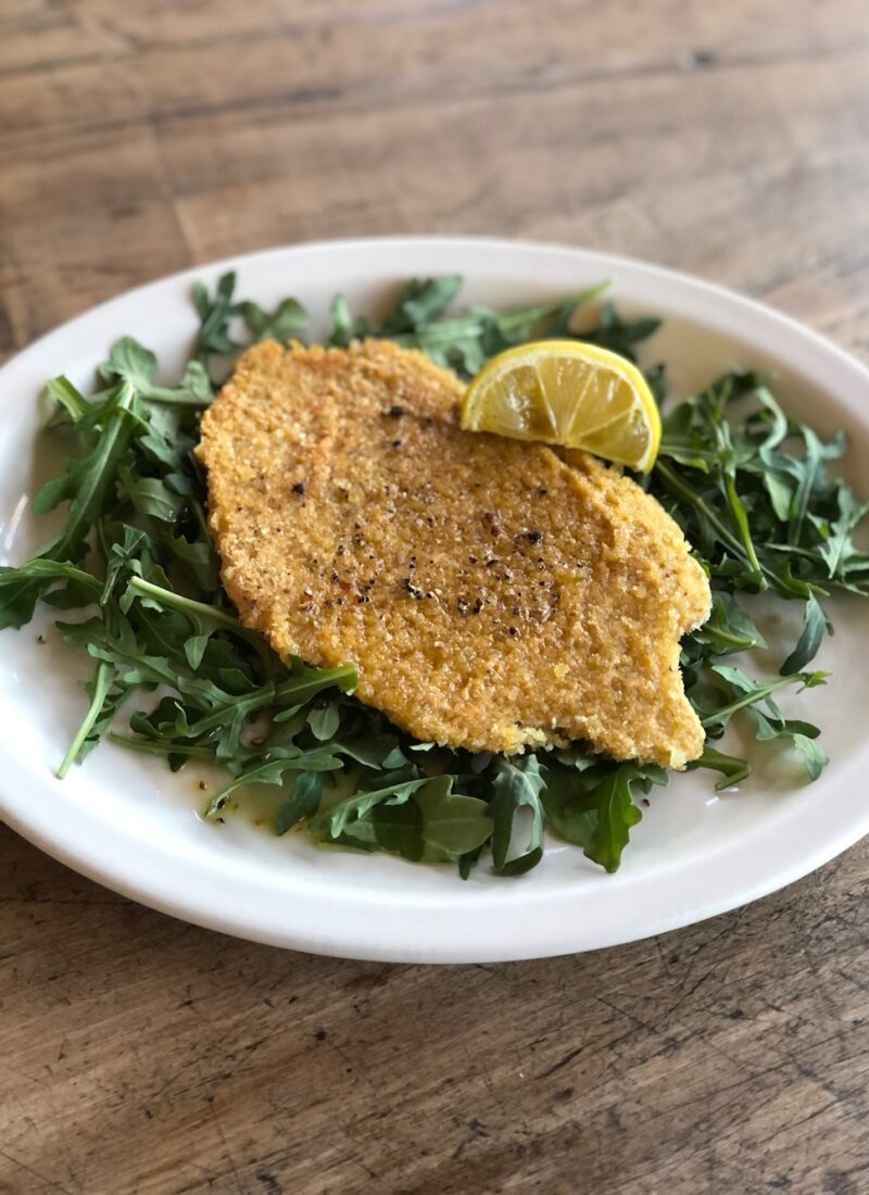 chickpea cutlet served on a bed of arugula.