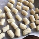 Homemade potato gnocchi on a tray.