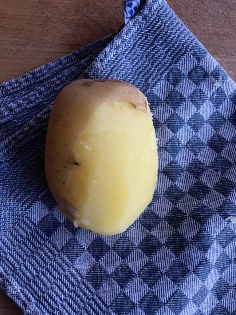 Peeling a potato to make potato gnocchi.