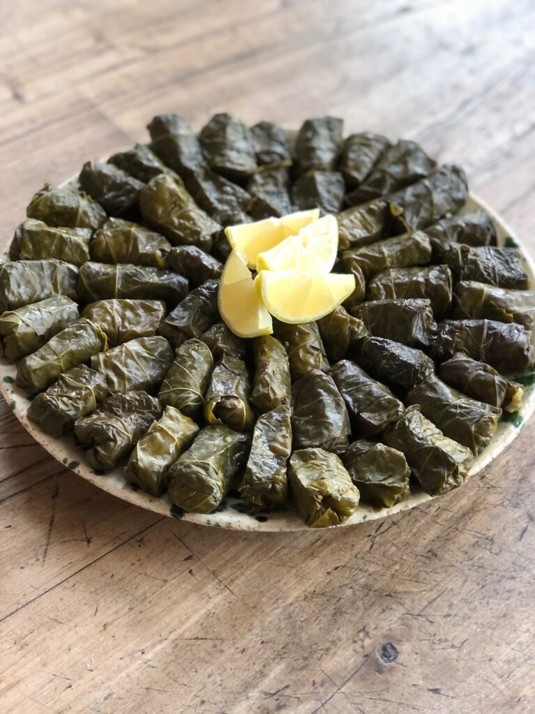 Homemade vegan stuffed grape leaves on a platter and garnished with lemon,