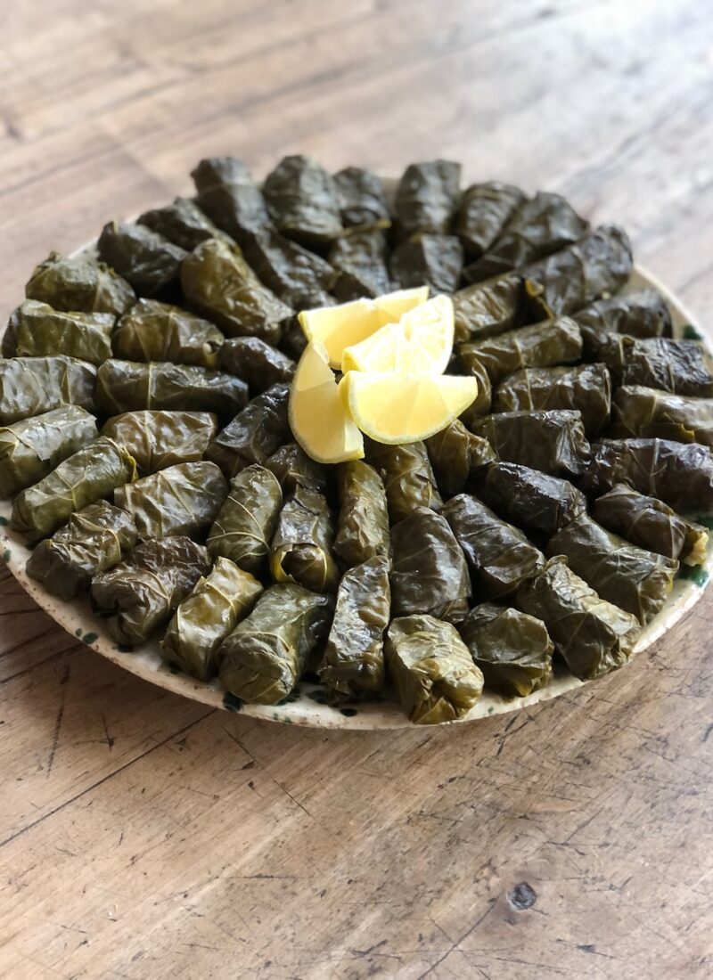 Homemade vegan stuffed grape leaves on a platter and garnished with lemon,