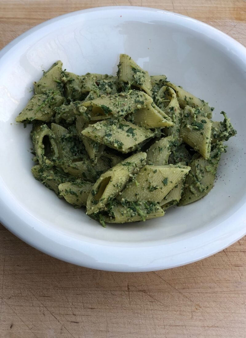 Vegan arugula pesto served on penne pasta.