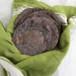 Cooked homemade blue corn tortillas in a basket ready to serve.