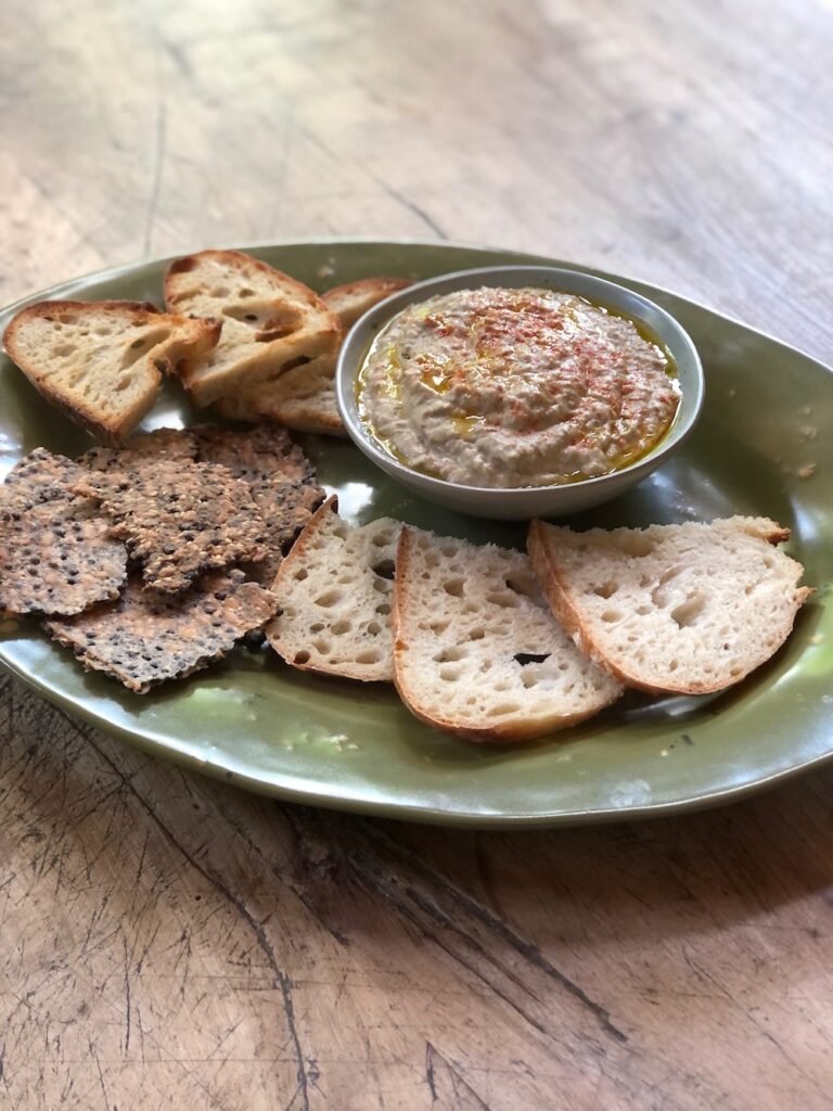 brown lentil hummus with crackers on a platter.