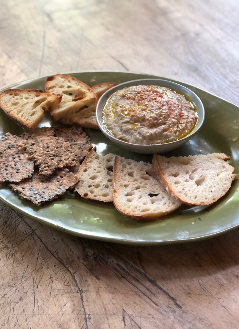 brown lentil hummus with crackers on a platter.